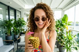 Donna che si rilassa bevendo un drink in un terrazzo smart con piante lussureggianti e automazioni